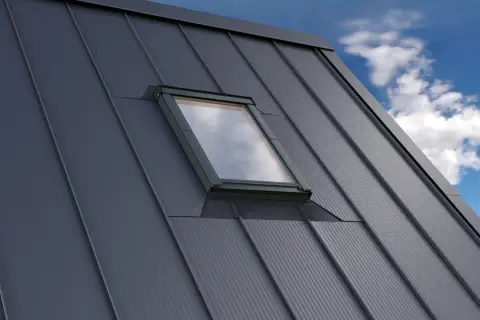 Szary dach z blachy z oknem dachowym. Detale obróbki okna dachowego podkreślają nowoczesny design.