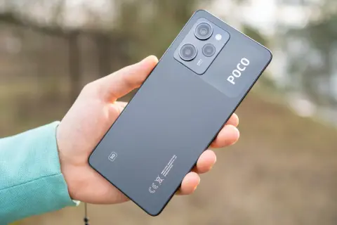 Dłoń trzyma ciemnoszary telefon POCO X5 5G z modułem aparatów i logo POCO.