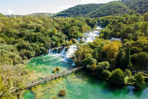 Atemberaubende Wasserfälle im Krka Nationalpark, Kroatien. Eine Holzbrücke führt Besucher über das smaragdgrüne Wasser.