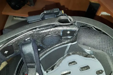 Montaż interkomu w kasku motocyklowym. Widoczne przewody i moduł komunikacyjny.