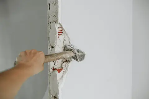 Mano golpeando un tabique con un mazo. ¡Demostrando que puedo tirar un tabique yo mismo!