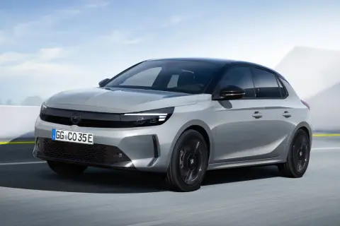 Grå Opel Corsa-e testkörs på en väg med en modern bakgrund.