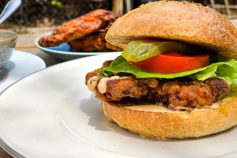 Burger maison au poulet croustillant et juteux, garni de laitue, tomate et cornichon.