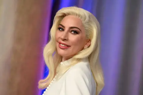 Lady Gaga med blont hår och vit klänning, ser ut som en stjärna som kan ha barn.