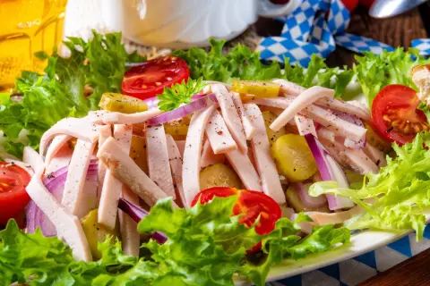 Ein leckerer Wurstsalat mit Tomaten, Gurken und Zwiebeln, perfekt für ein deftiges wurstsalat rezept. Dazu ein Glas Bier.