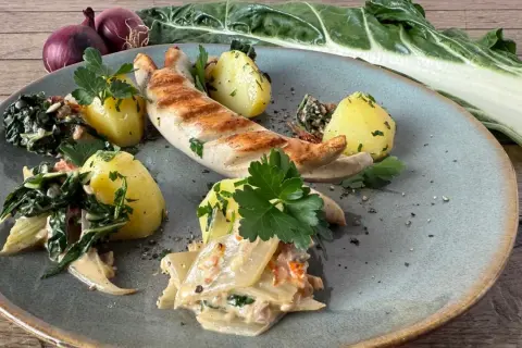 Gegrillte Wurst mit Salzkartoffeln und cremigem Gemüse. Ein Gericht, das zeigt, was gut zu Mangold passt.
