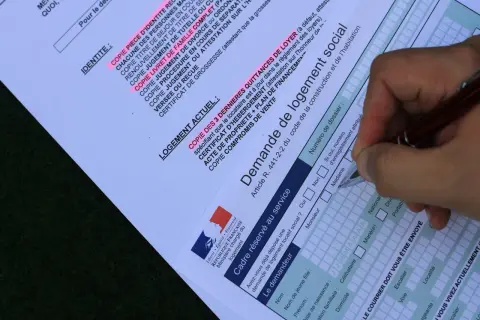 Formulaire de demande de mutation pour un logement social. Un stylo remplit les champs d'une demande de logement social.