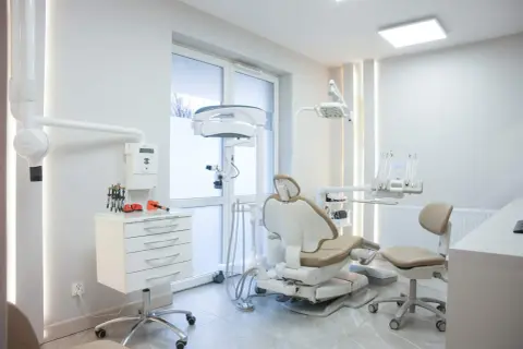 Nowoczesny gabinet stomatologiczny z fotelem dentystycznym i sprzętem.