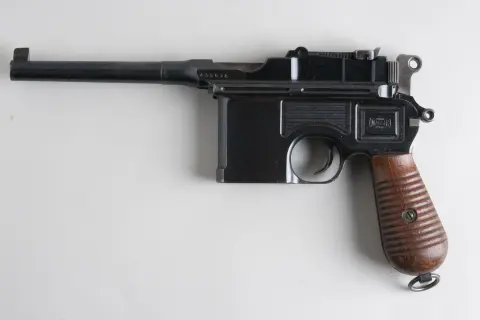 Czarny pistolet Mauser C96 z drewnianą rękojeścią, często uważany za pierwszy pistolet na świecie.
