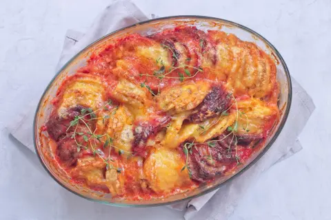 Un gratin patate douce aux tomates et fromage fondant, garni de thym frais, sort tout juste du four.