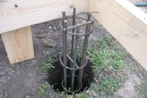 Zbrojenie słupa fundamentowego pod starym drewnianym domem. Przygotowanie do wylania betonu.