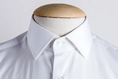 Dettaglio di una camicia bianca su manichino, che mostra i diversi tipi di collo camicia.