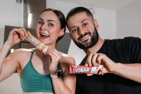 Ein glückliches Paar hält proteinriegel vor dem sport. Sie sind bereit für ihr Training mit EVOBAR.