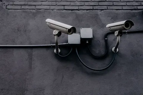 Dwie kamery monitoringu na szarej ścianie. Czy to tylko bezpieczeństwo, czy może coś więcej?