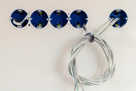 Instalacja elektryczna: jak podłączyć kabel 4 żyłowy do puszek gniazdek. Widać przygotowane do montażu puszki i zwinięty kabel.