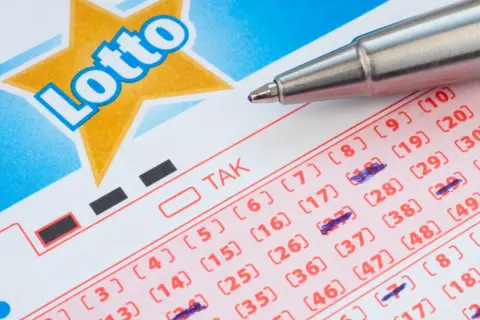 Kupon Lotto z zaznaczonymi liczbami, gotowy do gry w multi systemy na 3 liczby. Długopis czeka na kolejne wybory.