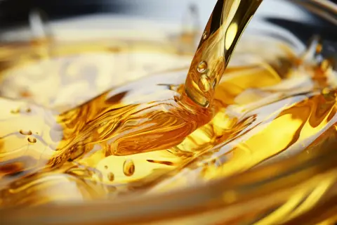 Goldener olus oil fließt in eine Schüssel und erzeugt faszinierende Wellen und Blasen.