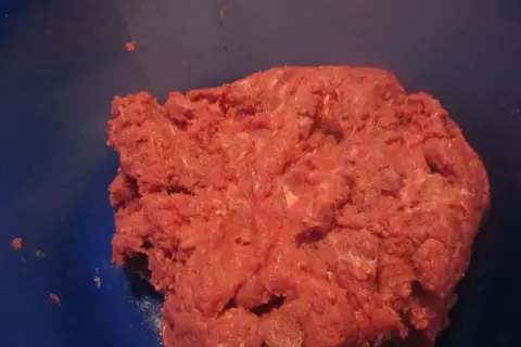 Frisches Hackfleisch, frisch gewolft, bereit für die Zubereitung von Frikadellen. Das gewolft bedeutungsvolle Fleisch liegt in einer blauen Schüssel.