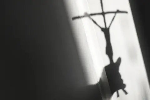 Schatten eines Kreuzes mit Jesusfigur, der eine kritische Auseinandersetzung mit evangelischen Freikirchen andeutet.