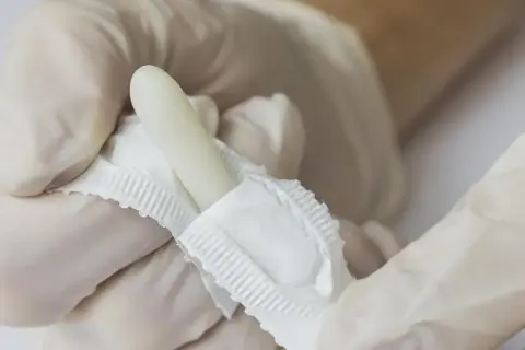 Ręce w rękawiczkach trzymają biały, torpedowy czopek.