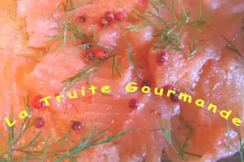 Carpaccio de truite finement tranché, parsemé de baies roses et d'aneth frais. Un délice gourmand.