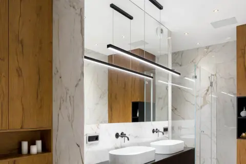 Bagno moderno con lavabi bianchi, specchio ampio e moderne idee illuminazione bagno con lampade a sospensione nere.