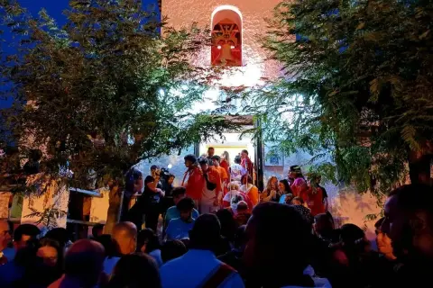 Multitud reunida frente a una iglesia iluminada, disfrutando de las fiestas de Calatayud.