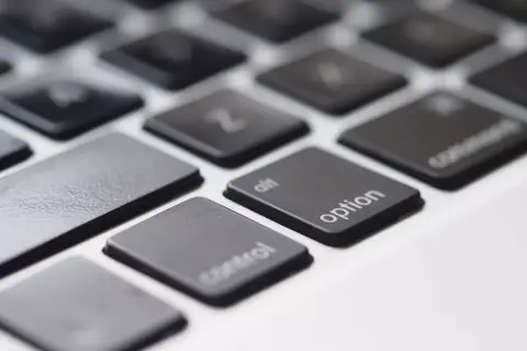 Zbliżenie na klawiaturę laptopa, widoczne klawisze "control", "alt", "option" i "command". Klawisz spacji jest pusty.