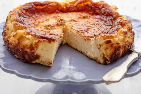Tarta de queso de la Viña, dorada y cremosa, servida en un plato morado.