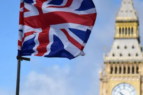 Flaga Wielkiej Brytanii powiewa przed Big Benem. Marzenie o podróży i uzyskaniu wizy do Londynu staje się realne.