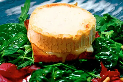Varm chevre chaud på rostat bröd, serverad med en fräsch sallad av spenat och ruccola. Smältande ost och gröna blad.