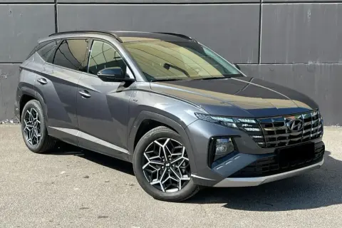 Szary Hyundai Tucson, jeden z najnowszych hyundai suv modele, z charakterystycznymi felgami i nowoczesnym designem, zaparkowany na tle szarej ściany.