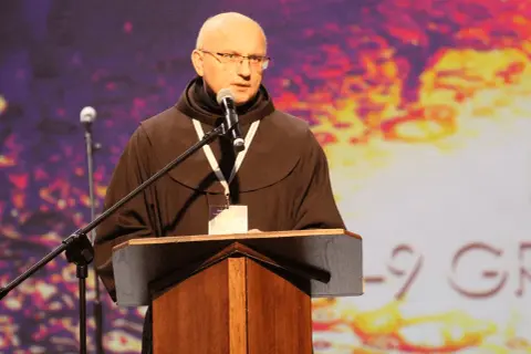 Ksiądz w habicie przemawia przy mównicy. Jego opinia kościoła jest ważna dla zgromadzonych.