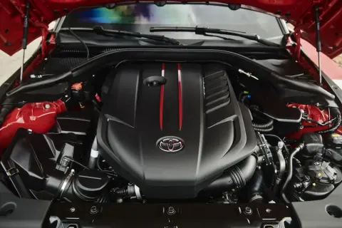El potente motor del Supra, con su distintivo logo de Toyota y detalles rojos, listo para la acción.