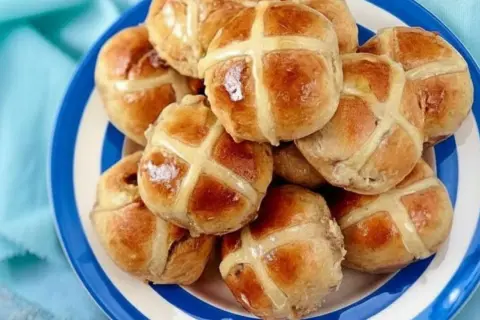 Ein Teller voller goldbrauner Hot Cross Buns, bereit zum Genießen.