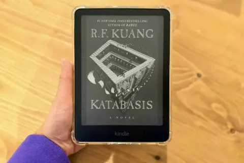 Main d'une personne tenant un Kindle Paperwhite affichant la couverture du livre "Katabasis" de R.F. Kuang.