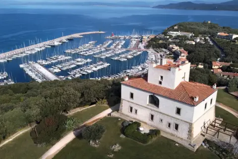 Punta Ala: un castello bianco con tetto rosso domina un porto turistico pieno di barche e il mare blu. Cosa vedere in questo luogo incantevole.