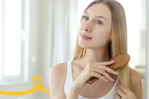 Kobieta szczotkuje włosy, przygotowując je na domowy peeling do skóry głowy.