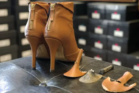 Bottes à talons aiguilles marron avec talons cassés, prêtes à réparer chaussures.