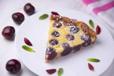 Une part de clafoutis aux cerises, saupoudrée de sucre glace, comme le ferait Cyril Lignac.