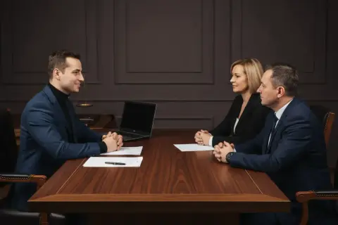 Trzy osoby przy drewnianym stole, laptop, dokumenty. Prawnik przedstawia potwierdzenie za zgodność z oryginałem.