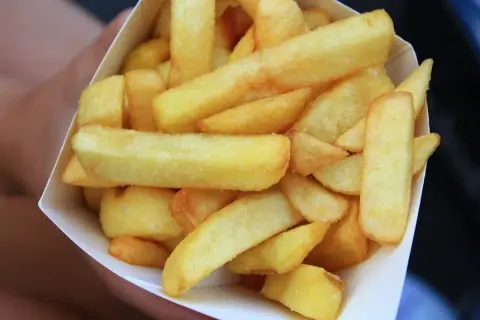 Złociste, grube frytki belgijskie w papierowym rożku.