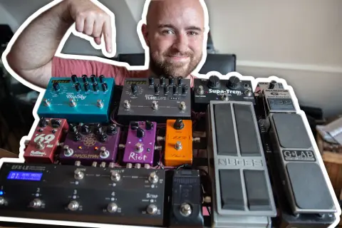 Uśmiechnięty mężczyzna pokazuje swoją bogatą kolekcję efektów gitarowych, prezentując ich kolejność na pedalboardzie.