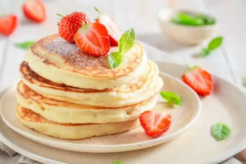 Puszyste pancakes z truskawkami i miętą, idealne na śniadanie. Prosty przepis na pyszne placki.