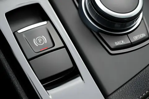 Bouton de frein à main électronique avec voyant rouge allumé, prêt à lâcher assurance. Le bouton "P" est visible.