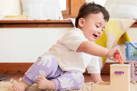 A baby's hand carefully places a toy, showcasing developing baby hand eye coordination.