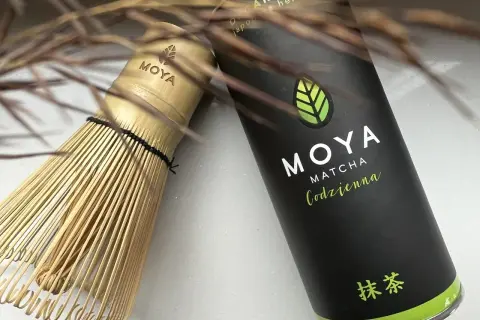 Tradycyjny bambusowy chasen obok puszki MOYA Matcha Codzienna. Idealne narzędzia, by poznać, co to matcha.
