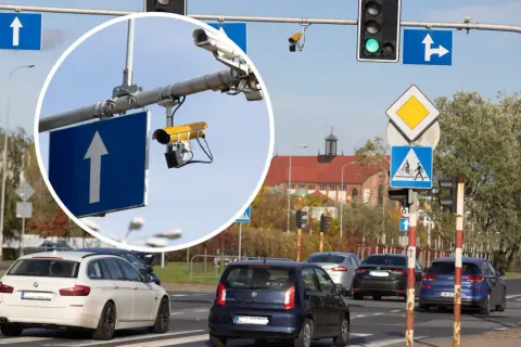 Kamery na skrzyżowaniach rejestrują wykroczenia. Widok na ruchliwe skrzyżowanie z sygnalizacją świetlną i znakami drogowymi.