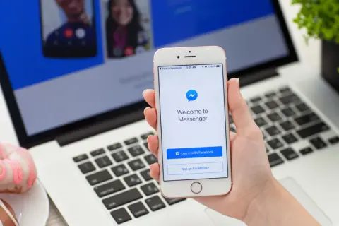 Jak włączyć dymki czatu w Messengerze na iPhone? Na ekranie telefonu widać ekran logowania do Messengera.