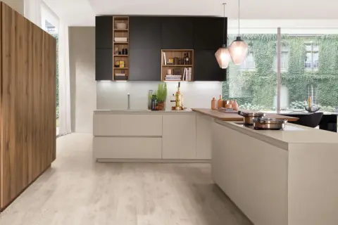 Une cuisine moderne avec des armoires noires et beiges, un îlot en bois et une grande fenêtre donnant sur un mur végétal. Une belle cuisine inspiration pour votre intérieur.
